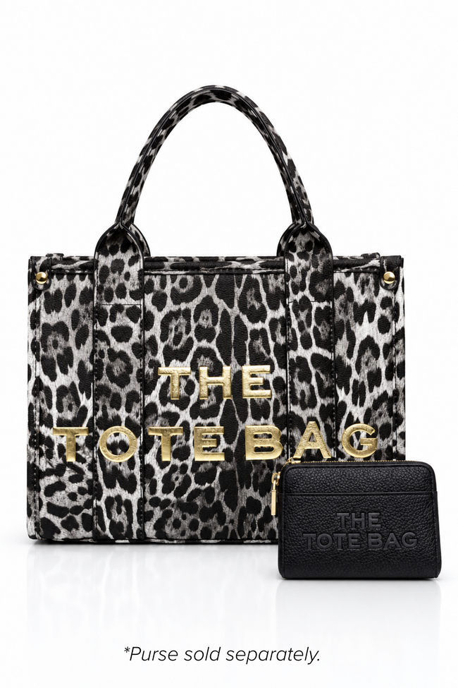 Leopard-print tote bag with a tan and dark brown animal print, two matching top handles, structured rectangular shape and bold gold-tone. "THE TOTE BAG" lettering on the front. Set against a white background. With a black Tote purse pictured in front.