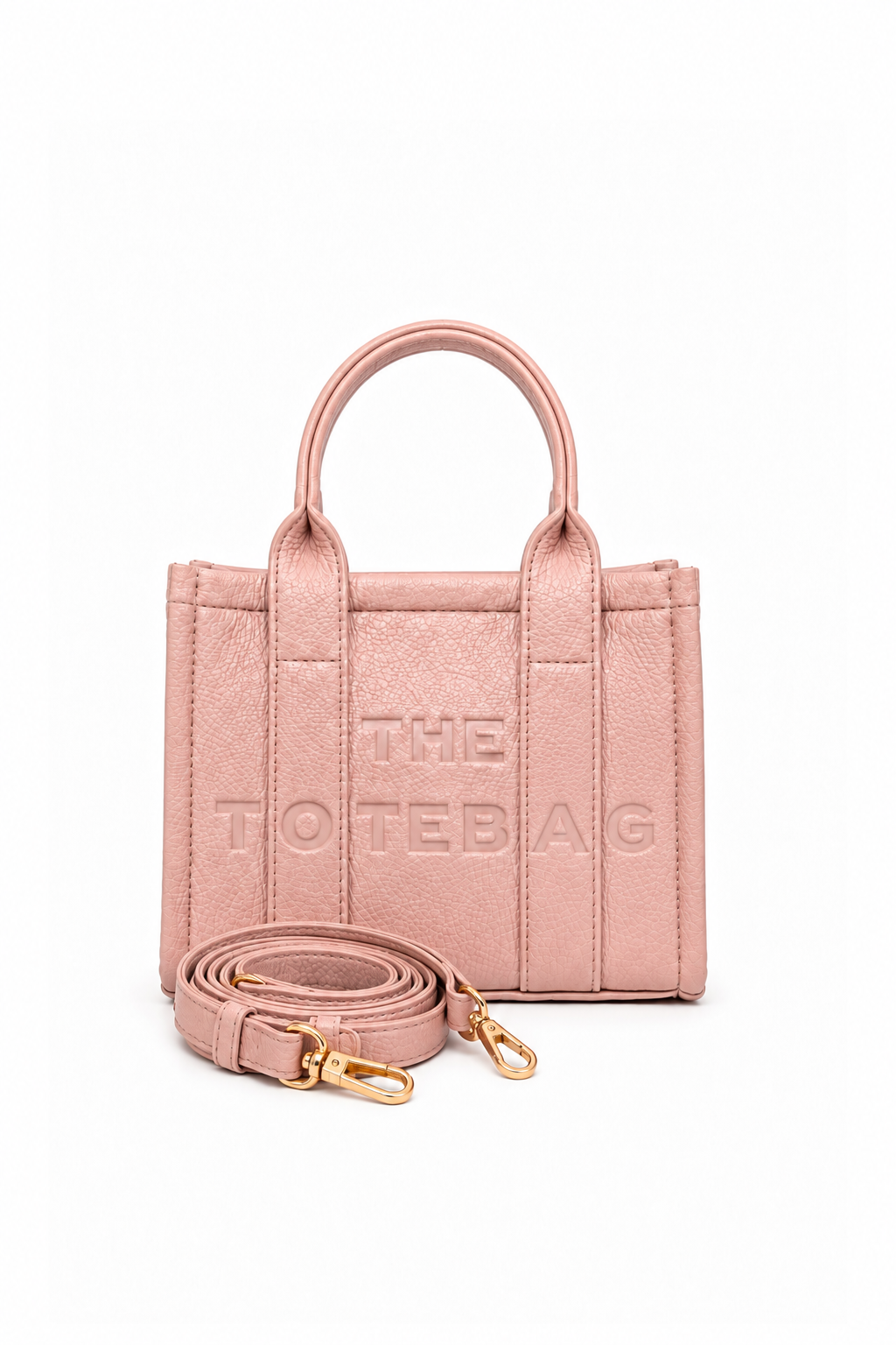 Pink faux leather structured tote bag with two rounded top handles, embossed. "THE TOTE BAG" lettering on the front, vertical stitched panels, contrast edging and gold- tone stud details. With pink-tone strap pictured in front of the bag.