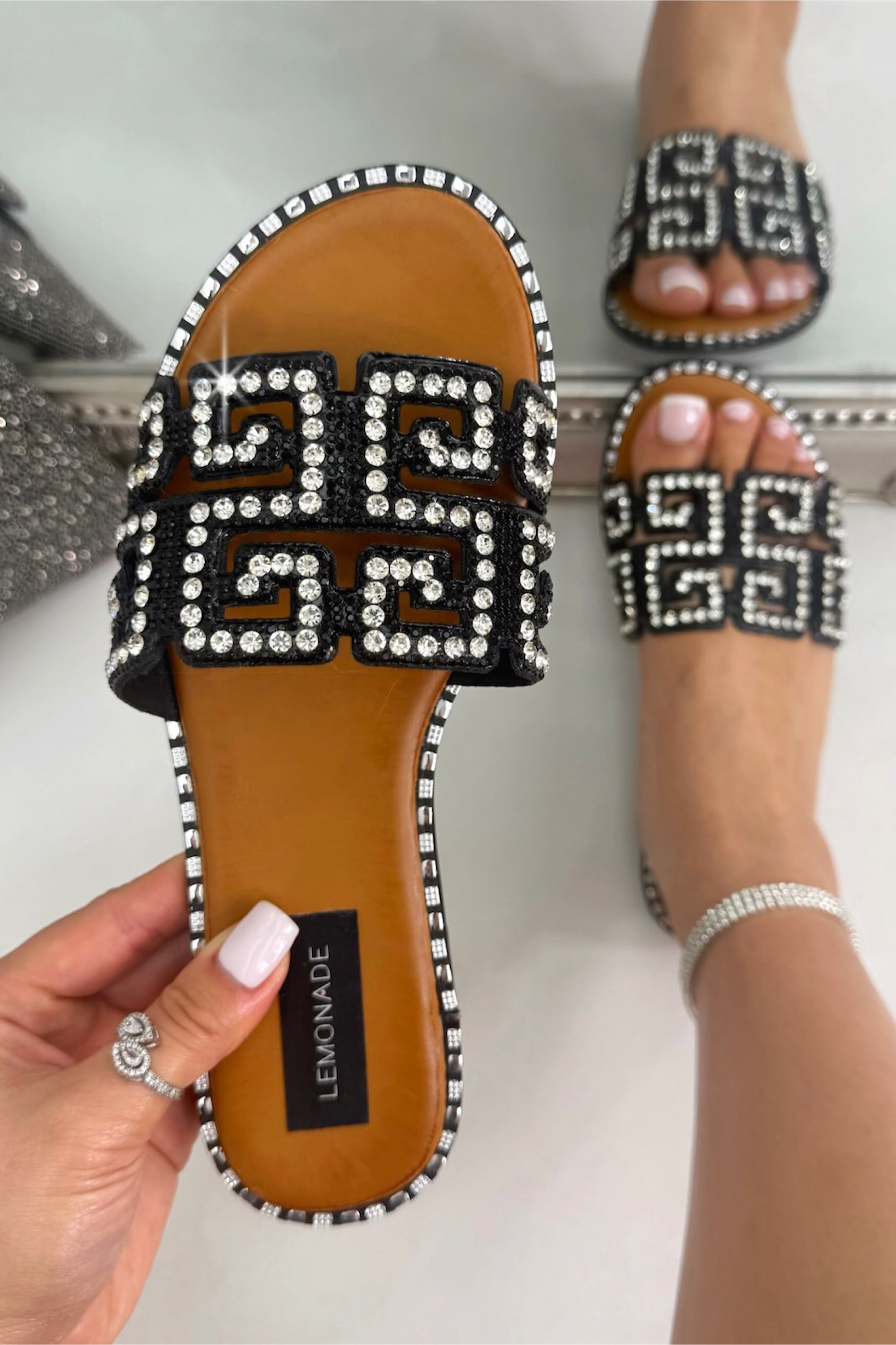 Beaded sandals with a brand label on a neutral background