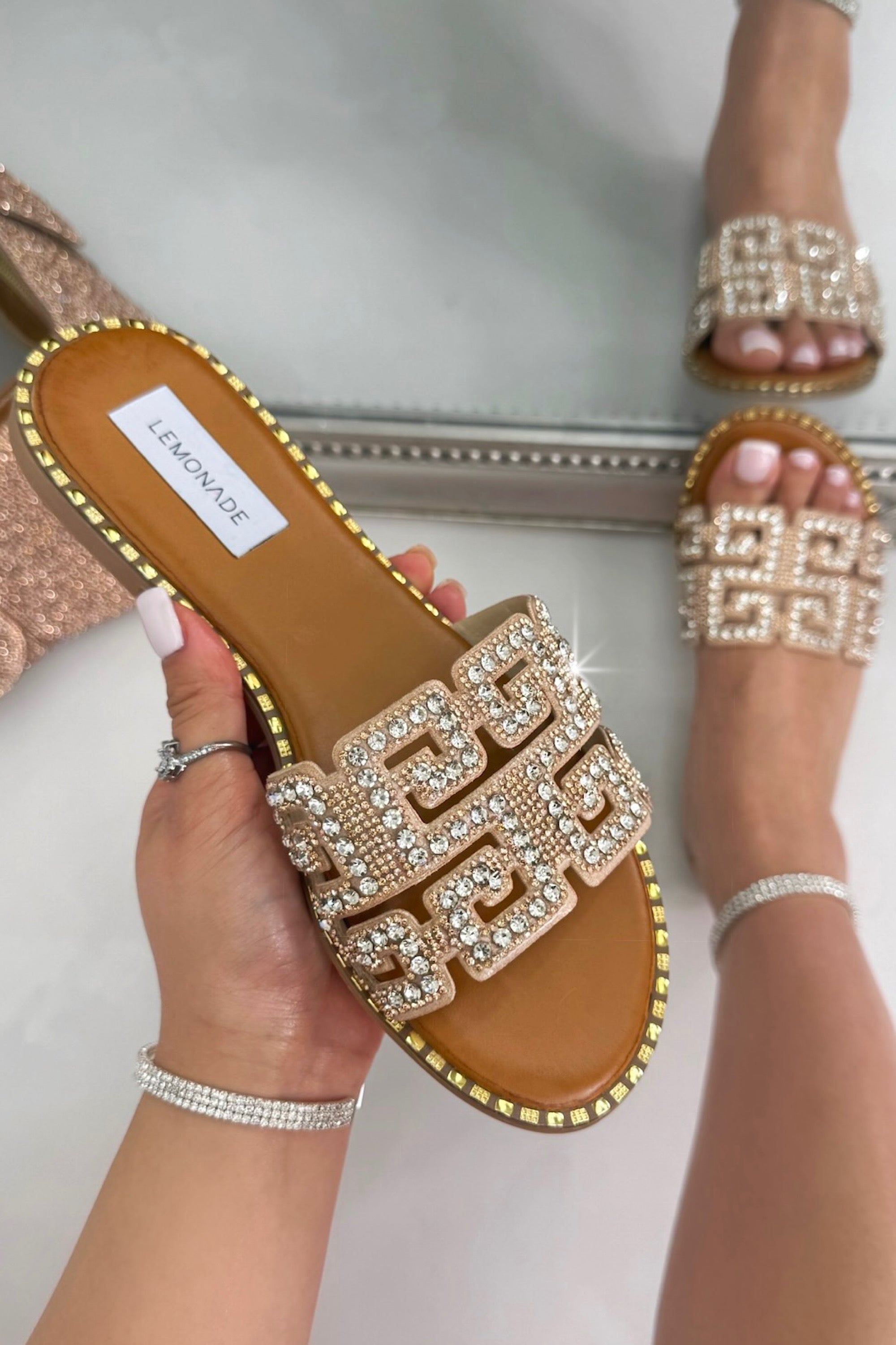 Pink embellished sandals being held in hand