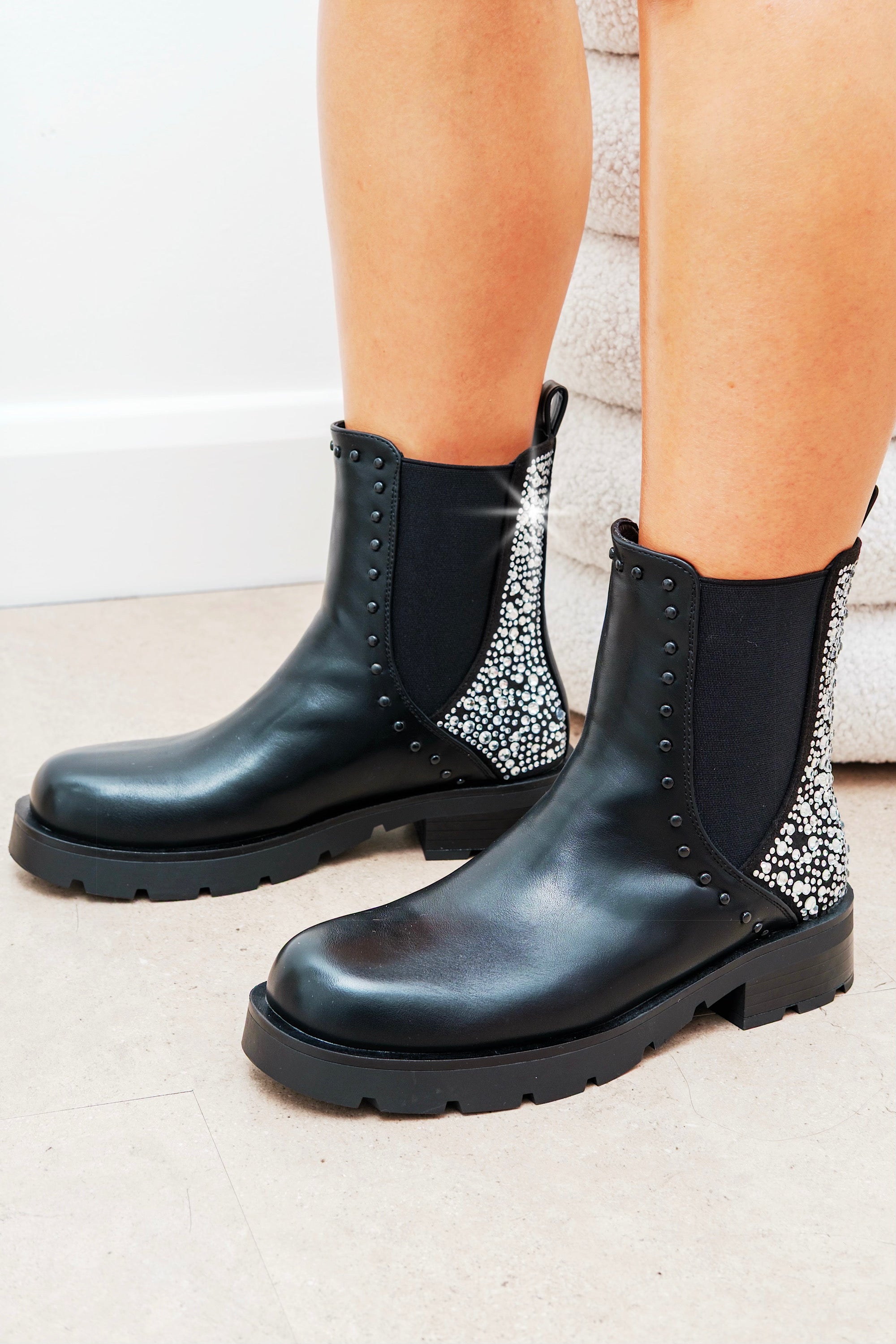 Black Chelsea boots with decorative elements on a neutral background