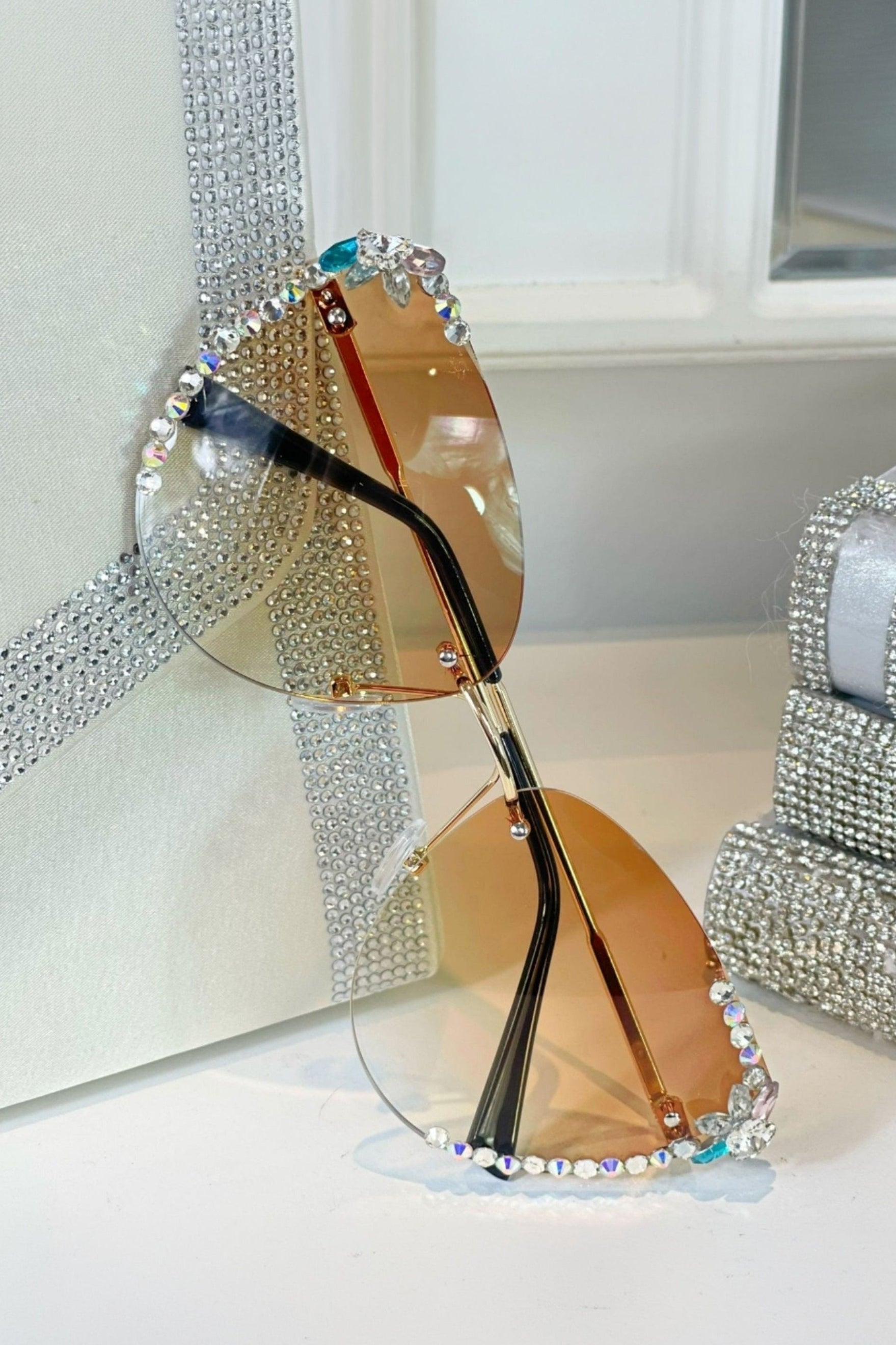Sunglasses with decorative rhinestone frame on a white surface