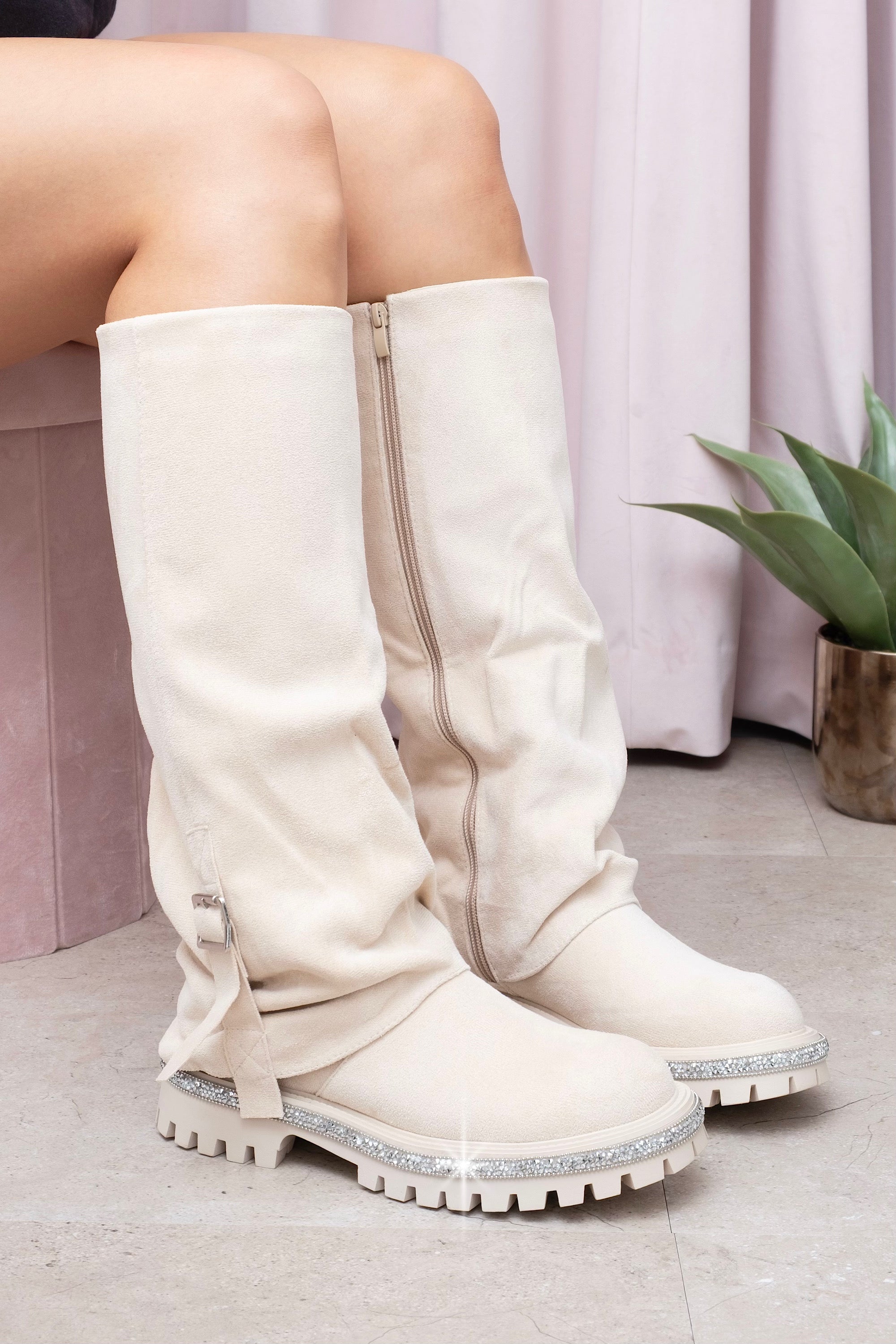 Nude knee-high boots with rhinestone sole worn by a person, against a light background.