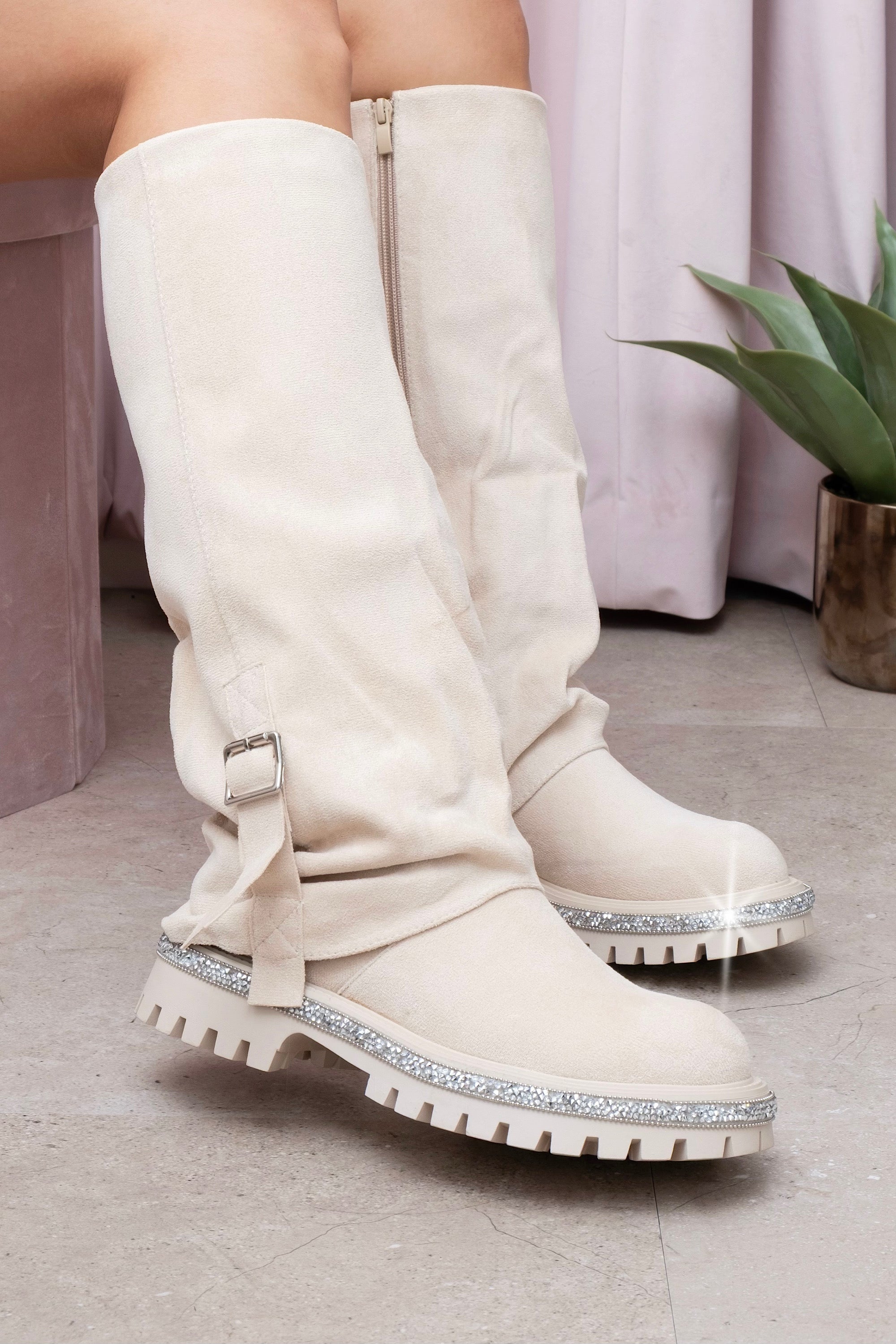 Nude knee-high boots with glittery sole on a light wooden floor.