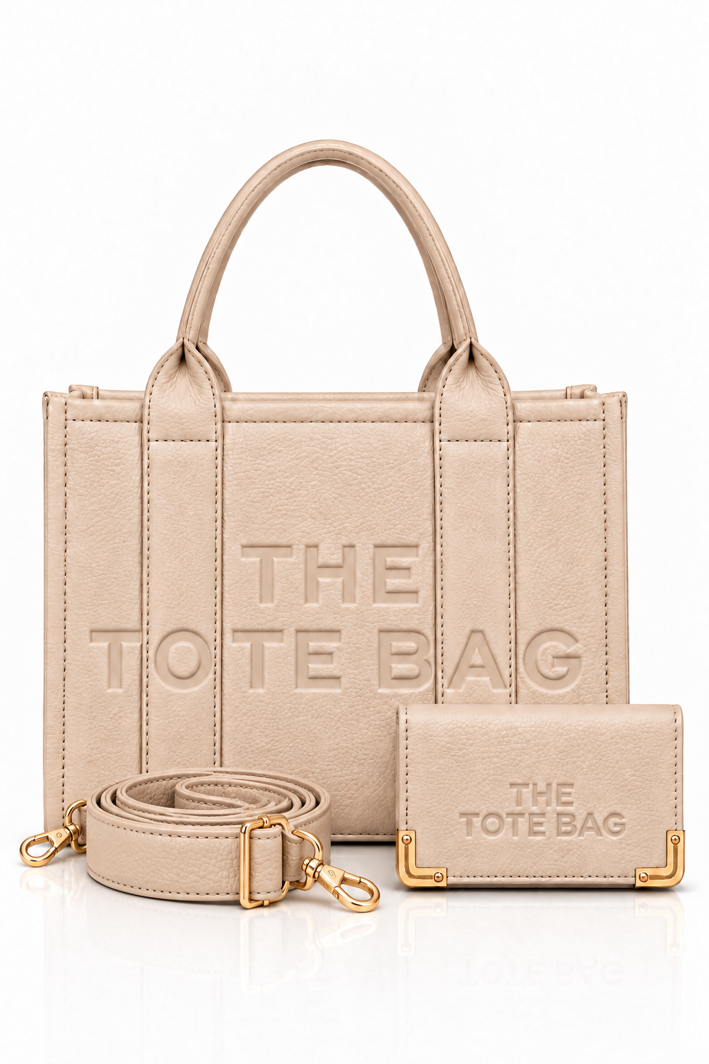 Nude tote bag with short rounded handles, matching vertical from straps, embossed "THE TOTE BAG" lettering, paired with a matching gold zip around wallet. Nude shoulder strap and matching purse pictured in front.