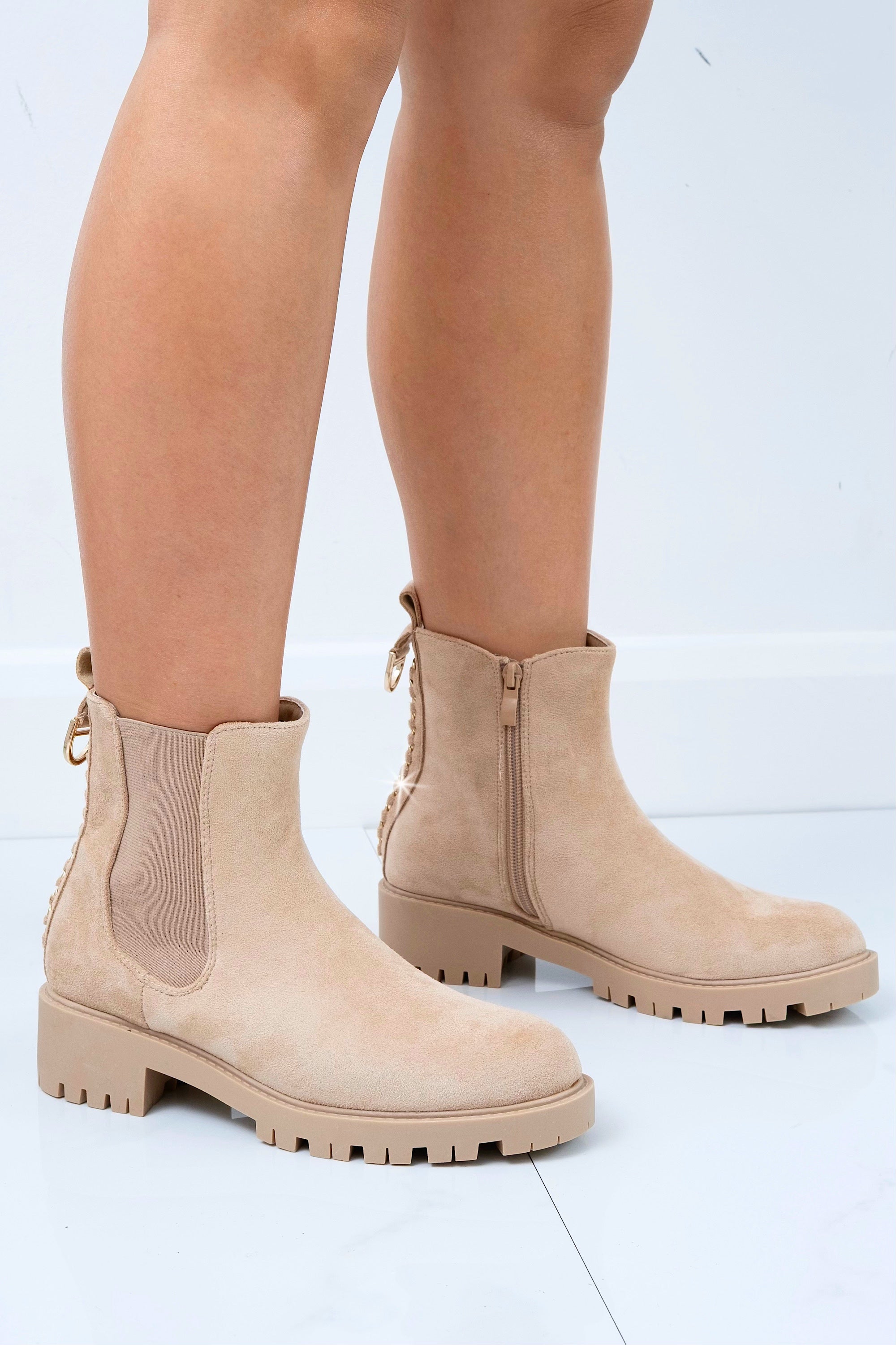 Beige Chelsea boots worn by a person on a light gray background