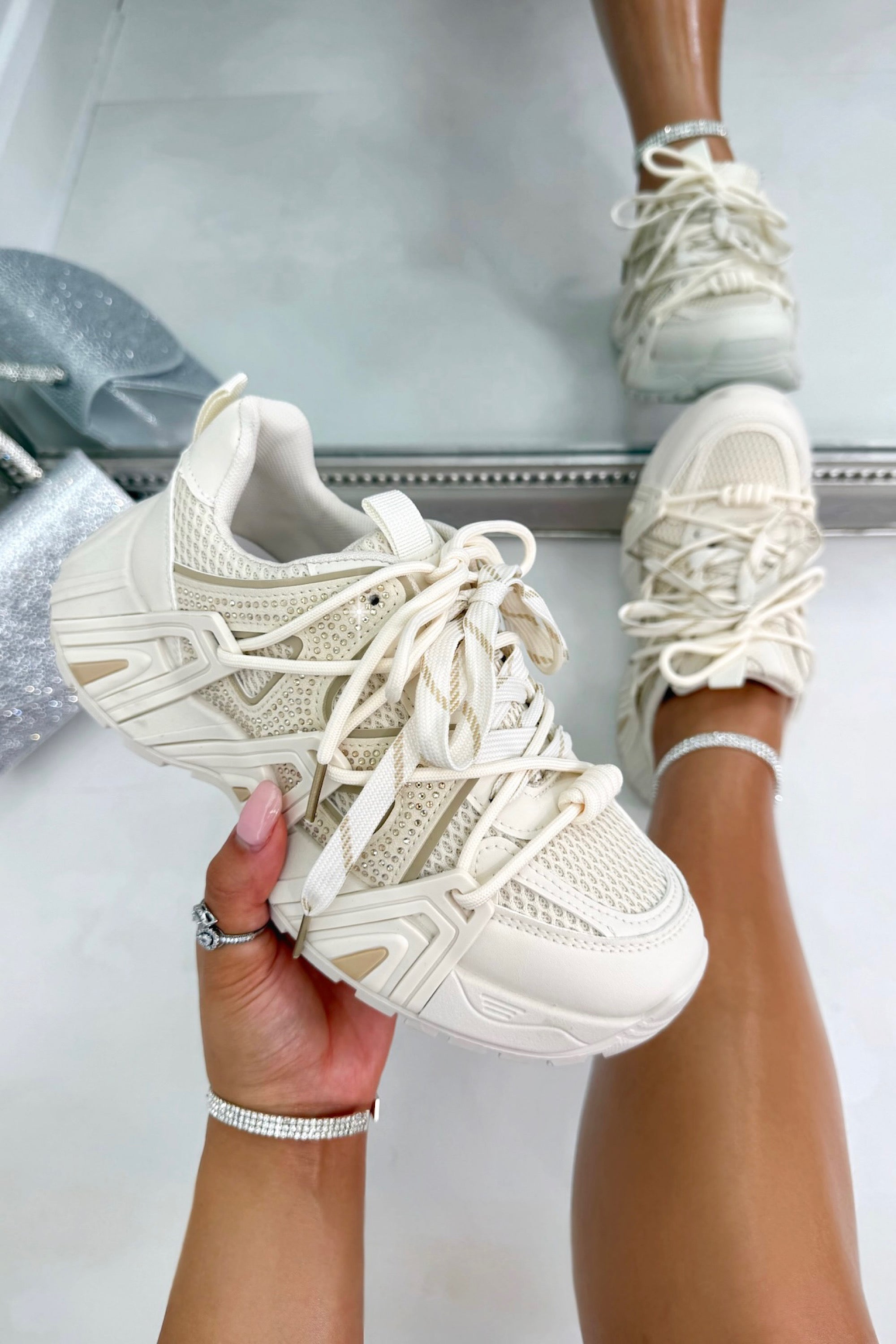 Beige sneakers being held with a blurred background