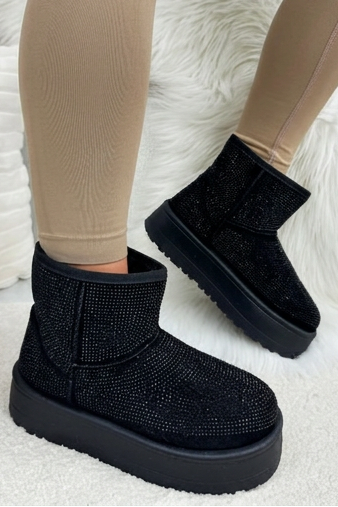 Black platform boots worn with beige leggings on a white textured surface