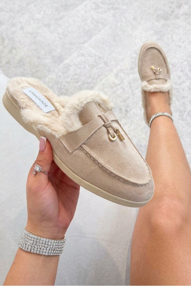 Beige slippers being worn on a light gray floor.