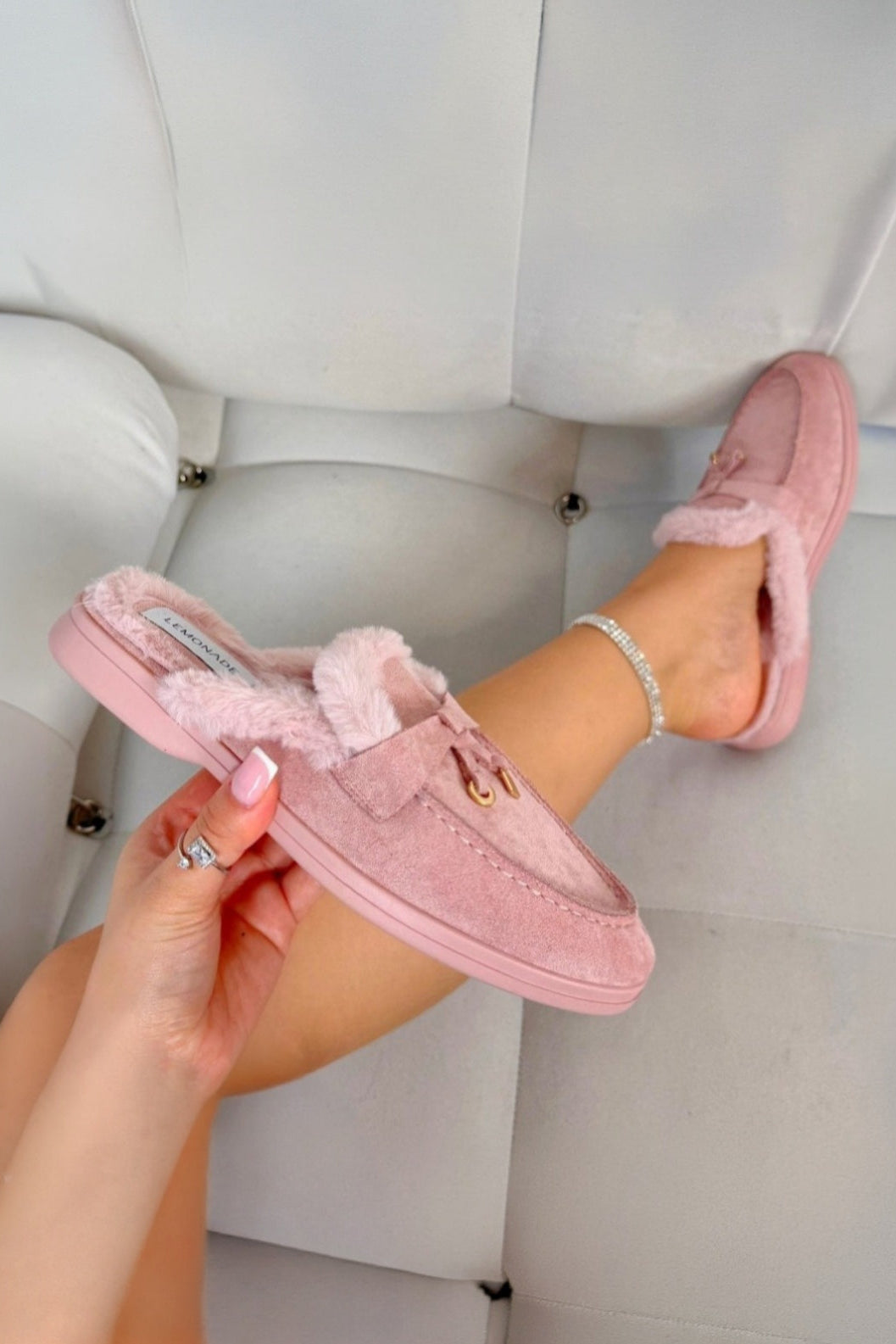Pink slippers being held with a white background