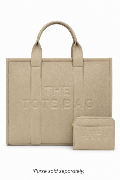 Beige faux leather structured tote bag with two rounded top handles, embossed. "THE TOTE BAG" lettering on the front, vertical stitched panels, contrast edging and gold- tone stud details. With beige-tone tote purse pictured in front of bag. 