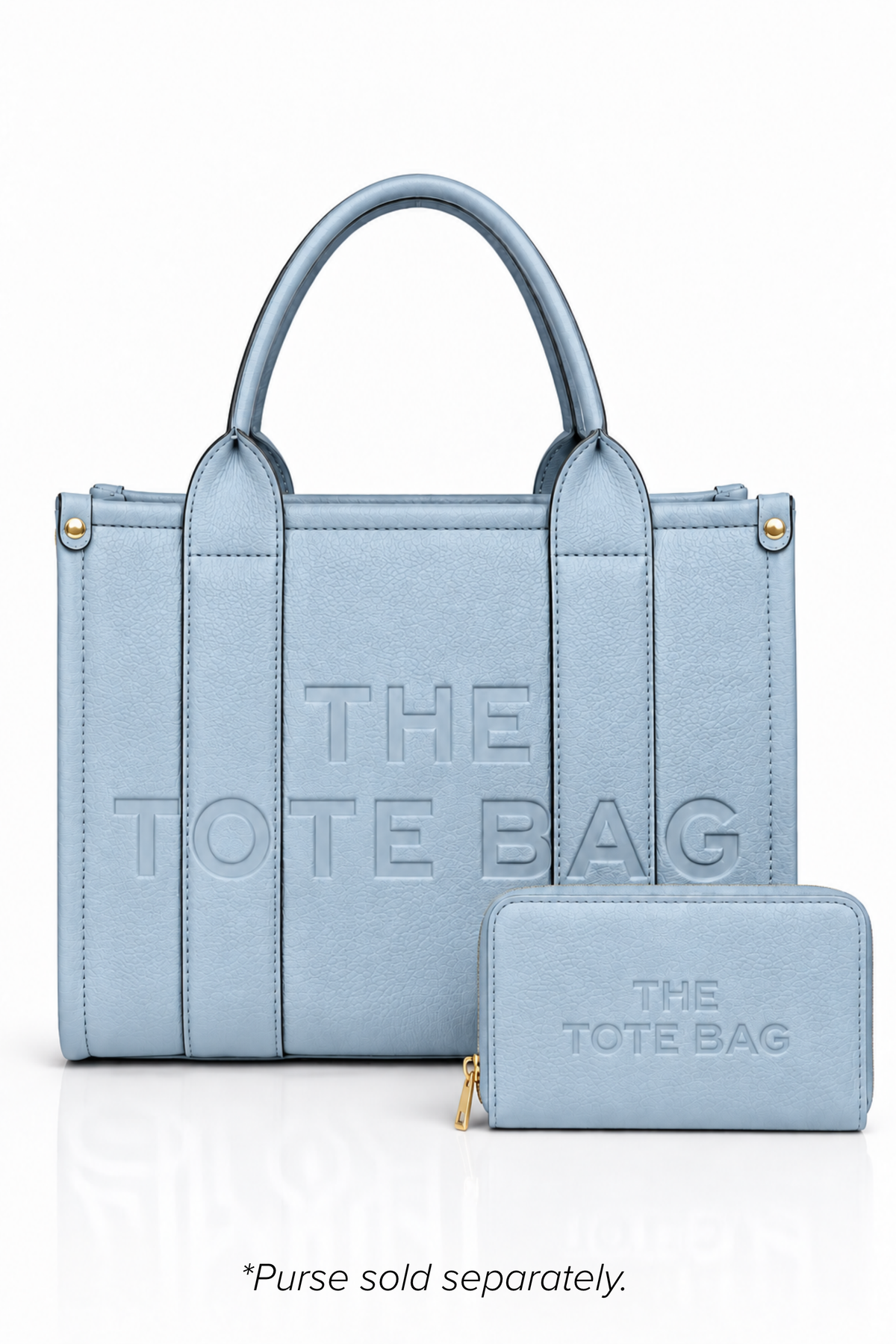 Blue faux leather tote bag with two rounded top handles, embossed "THE TOTE BAG" lettering on the front, contrast stitching, gold tone hardware with a blue Tote purse pictured in front of bag.