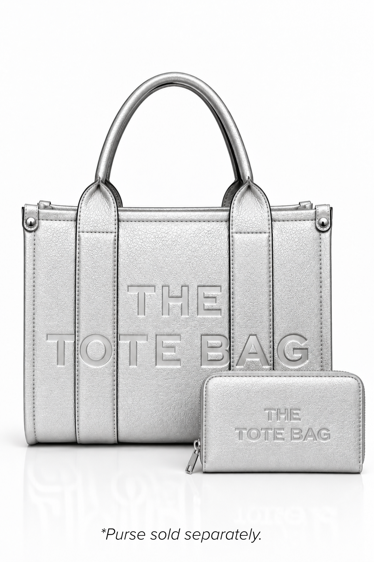 Metallic Silver structured tote bag with two rounded top handles, embossed. "THE TOTE BAG" lettering on the front, vertical stitched panels, contrast edging and gold- tone stud details.  Metallic Silver Tote purse pictured in front. Set against a white background.