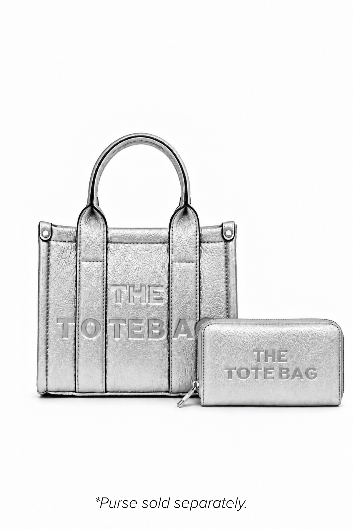 Silver mini structured tote bag with two rounded top handles, vertical stitched panels, matching tonal stitching and subtle embossed "THE TOTE BAG" lettering on the front. Shown with matching decorative key ring and rectangular zip purse. Purse and keyring sold separately.  