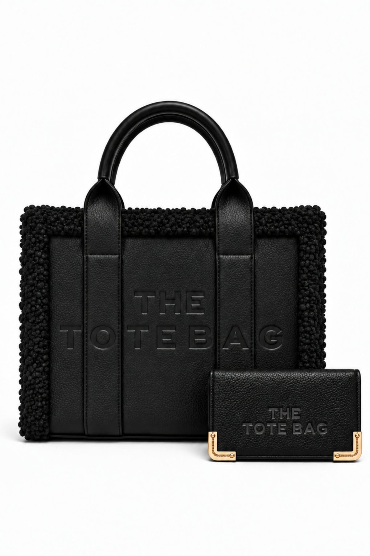 Black tote bag bundle featuring a structured handbag with rounded top handles, textured trim, embossed "THE TOTE BAG" lettering, and matching black straps. Includes a matching black purse with embossed branding and gold-tone corner detailing.