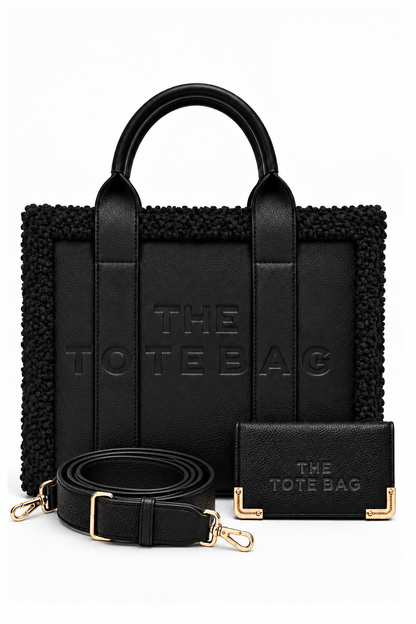 Black tote bag bundle featuring a structured handbag with rounded top handles, textured trim, and embossed "THE TOTE BAG" lettering. Includes a matching black purse with gold-tone corner detailing and an adjustable, detachable shoulder strap with gold tone clips. 