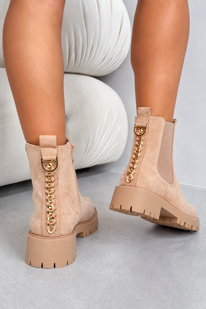 Beige suede ankle boots with gold chain and D-ring hardware, shown on a model&