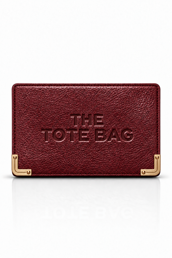 A burgundy textured leather tote bag with gold-tone metal corner brackets and embossed text reading &