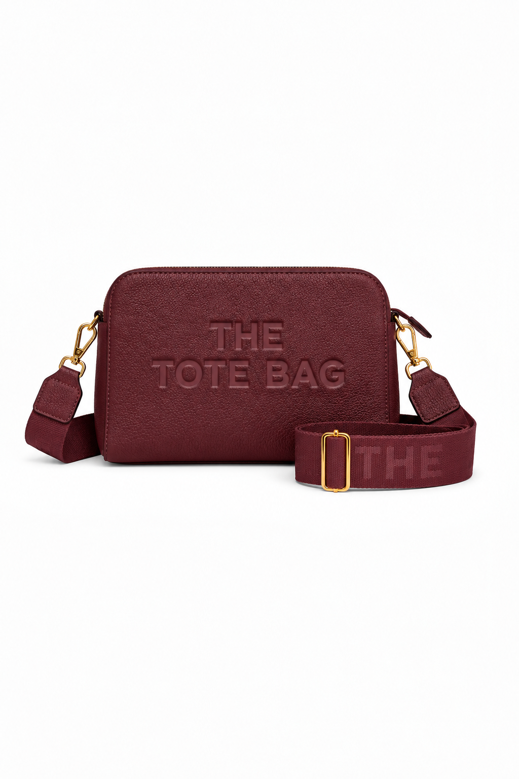 Burgundy cross body bag with a rectangular shape, rounded corners, embossed, "THE TOTE BAG" lettering on the front, gold-tone clips and a wide adjustable matching shoulder strap with a gold tone buckle. 