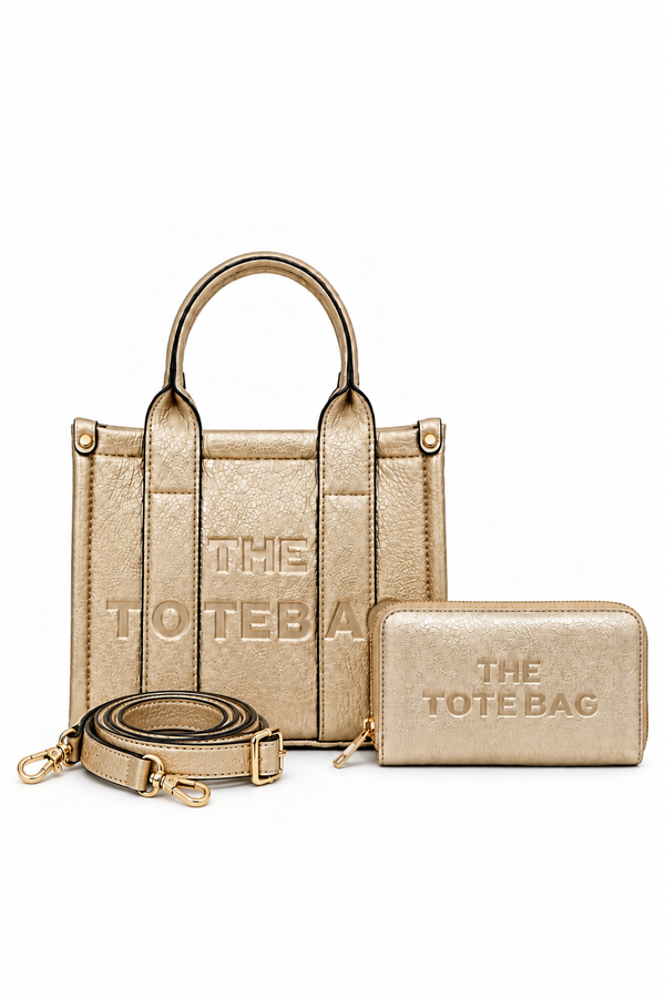 Champagne textured tote bag with short rounded handles, matching vertical from straps, silver-tone stud details and embossed "THE TOTE BAG" lettering, paired with a matching gold zip around wallet.  Set on a white background.