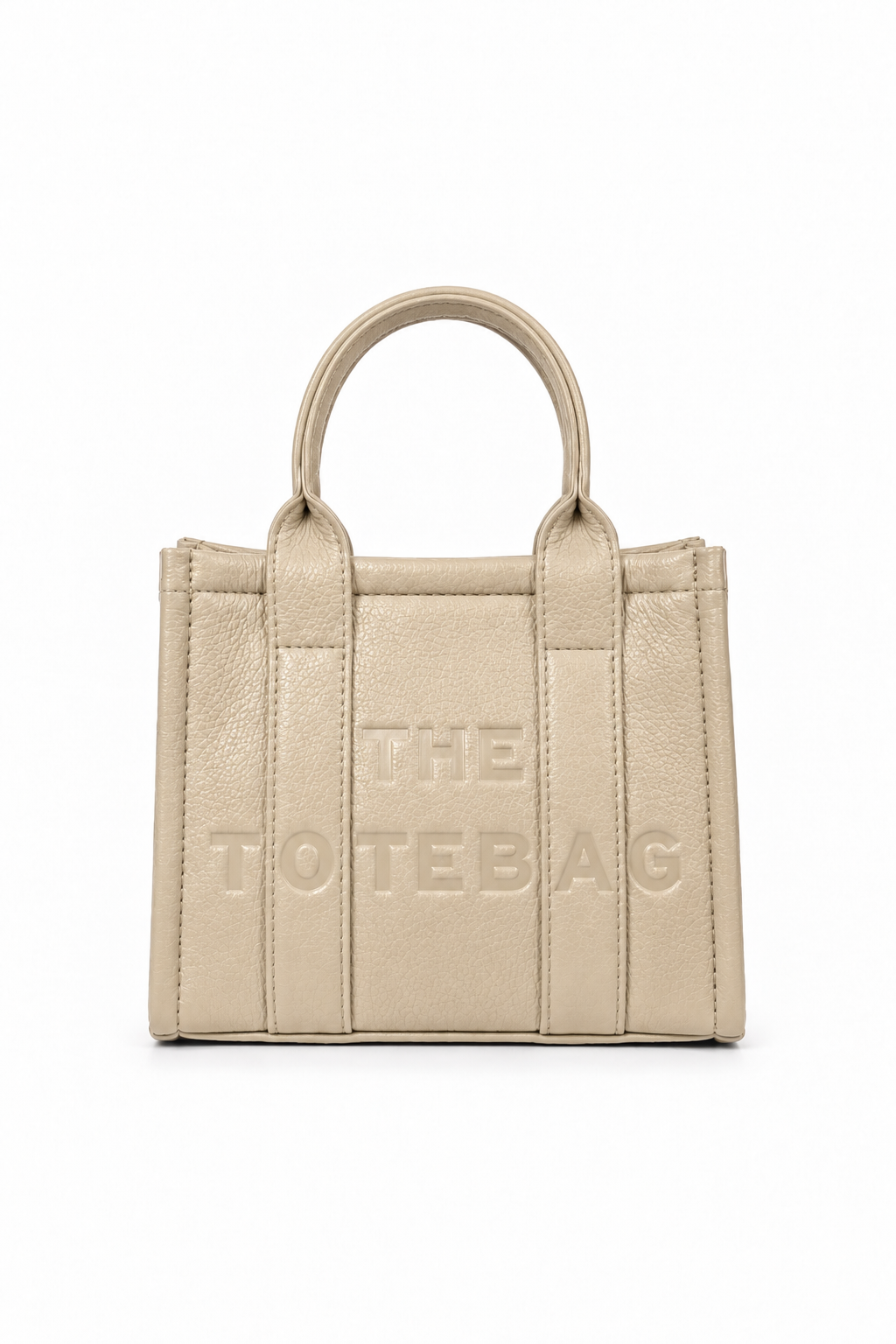 Beige mini faux leather structured tote bag with two rounded top handles, vertical stitched panels, matching tonal stitching and subtle embossed "THE TOTE BAG" lettering on the front. 