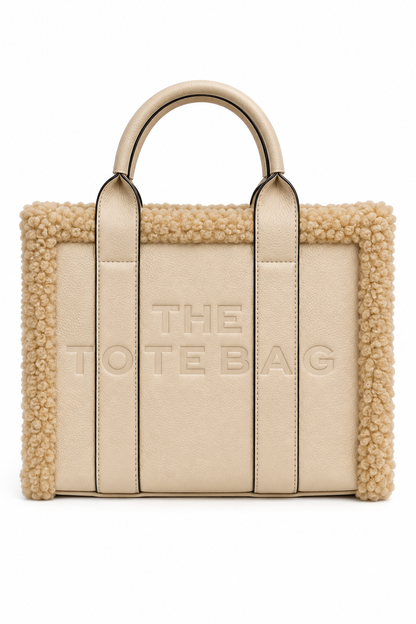 Nude Tote bag featuring a plush cream bouclé trim, structured silhouette, long top handles with black edging, and raised tonal lettering on the front. Set against a white background.