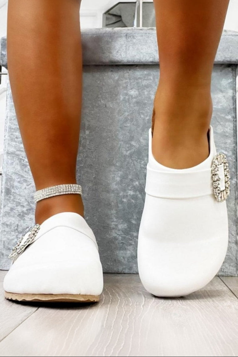 White loafers with decorative elements worn indoors.