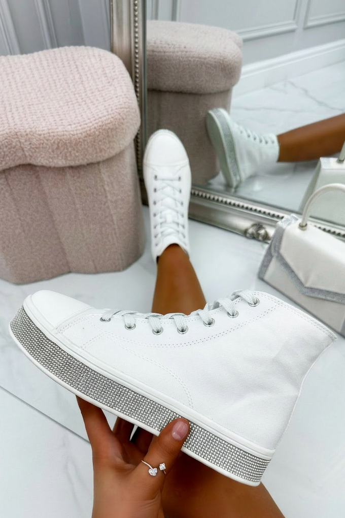 Person holding a white sneaker with gray sole in front of a mirror.
