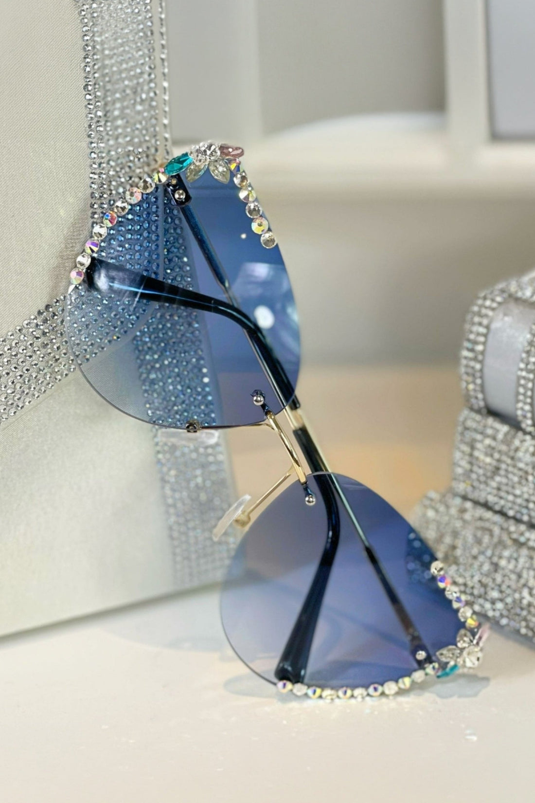 Blue sunglasses with rhinestone embellishments on a light background