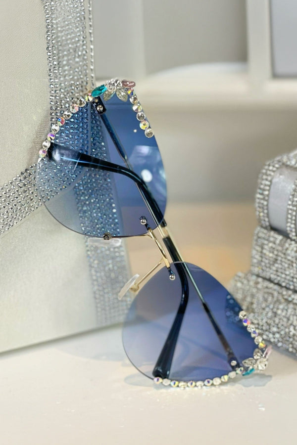 Blue sunglasses with rhinestone embellishments on a light background