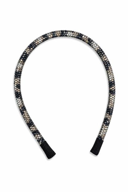 A braided headband with a black, white, and beige leopard pattern, finished with solid black fabric tips, shown on a plain white background.