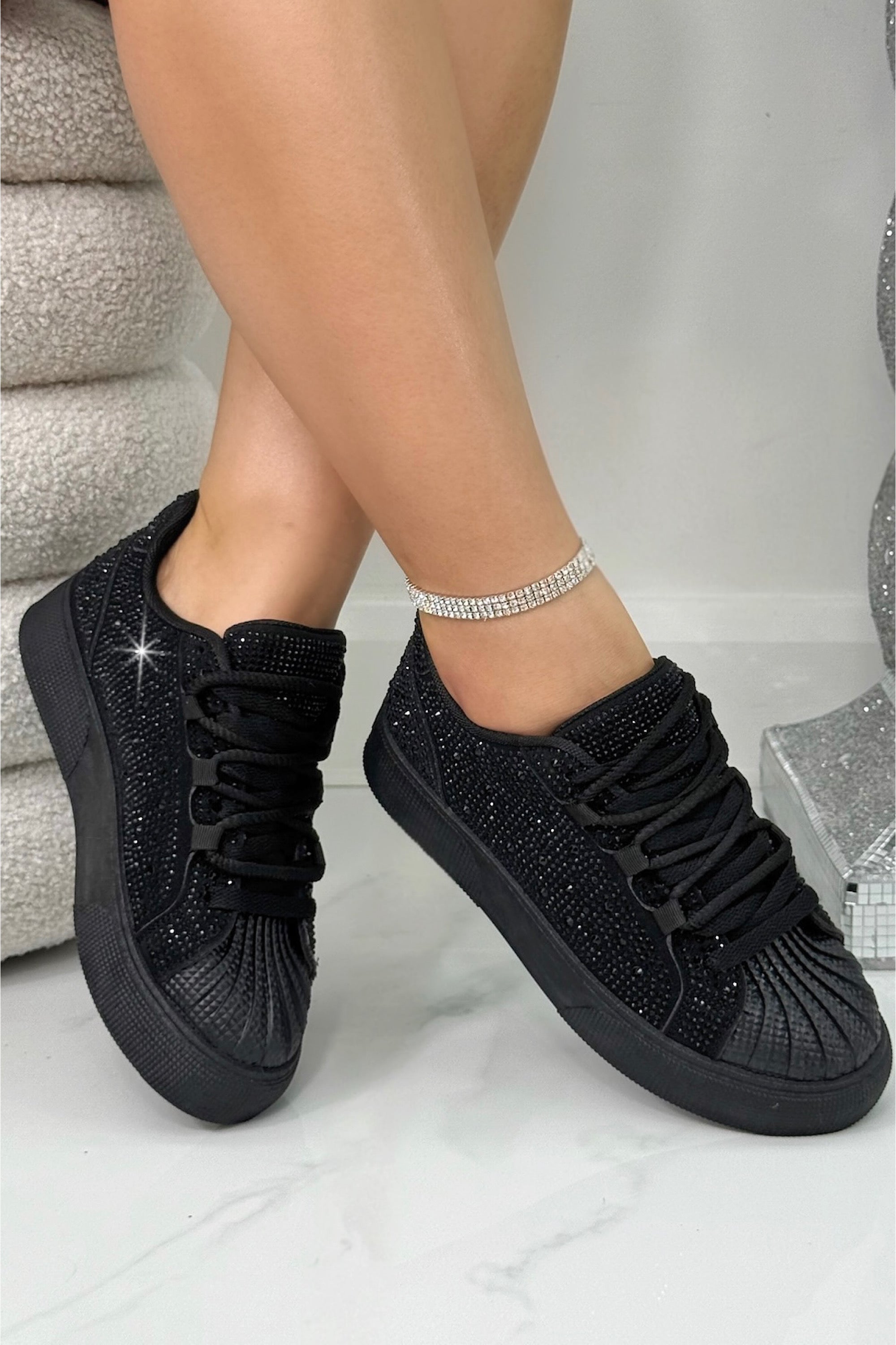 Black glittery sneakers worn by a person on a light background