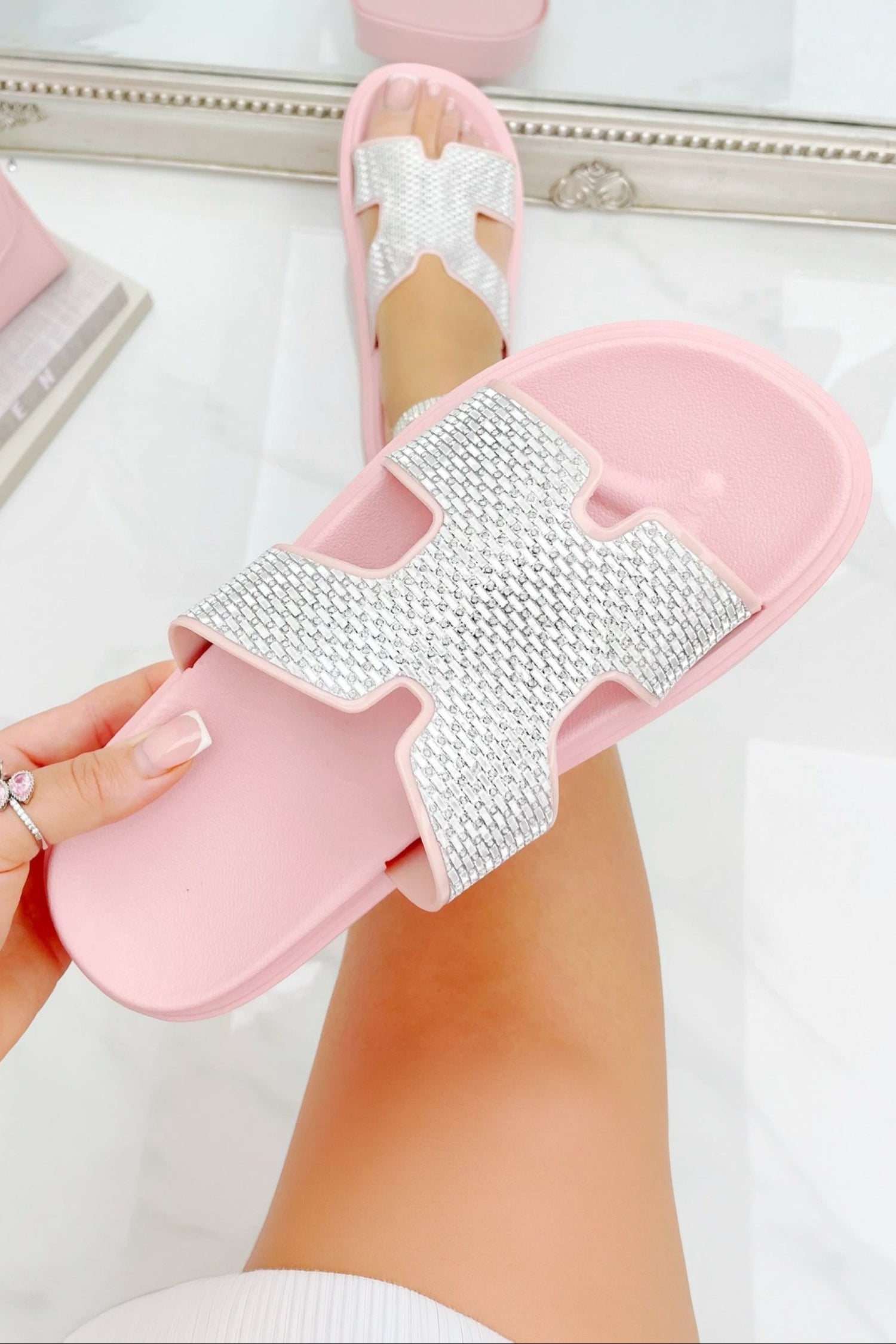 Pink slider with rhinestone design worn by a person on a white background