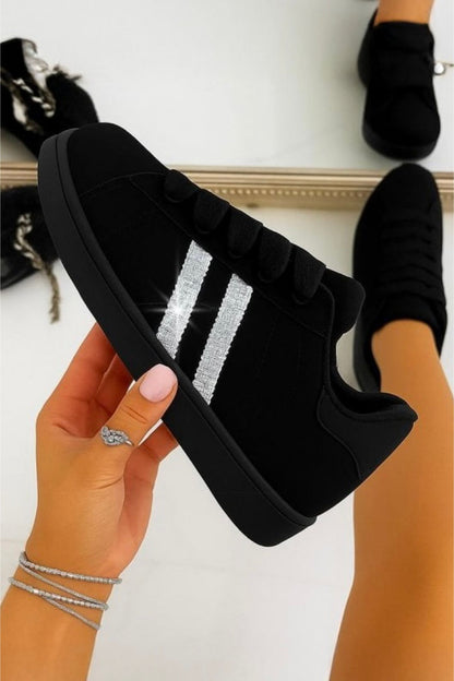 Black sneakers with white stripes held by a hand, with a blurred background