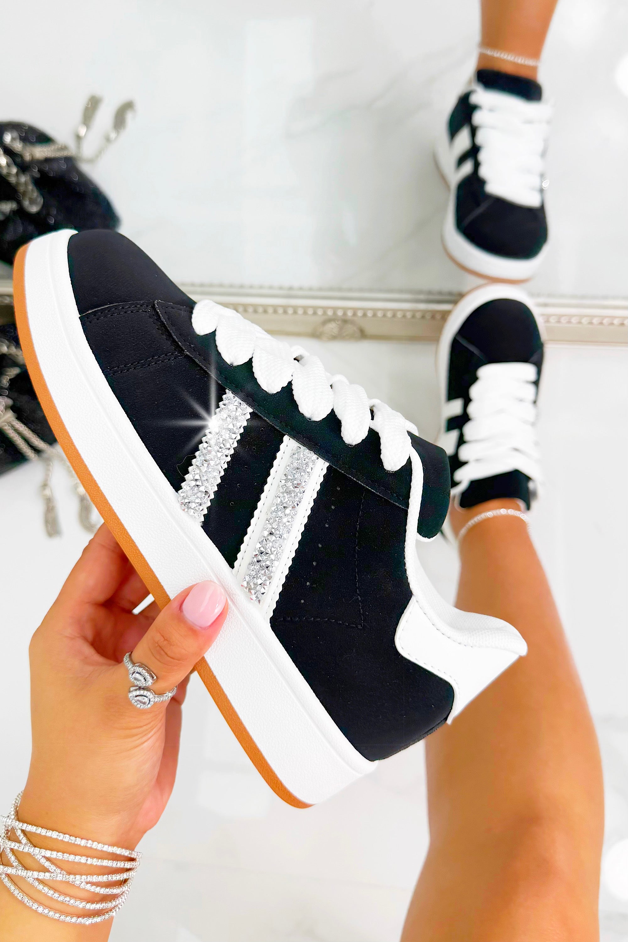 Black and white sneaker with decorative elements held by a hand against a neutral background