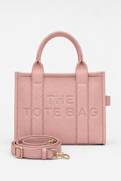 Dusty Rose faux leather structured tote bag with two rounded top handles, embossed. "THE TOTE BAG" lettering on the front, vertical stitched panels, contrast edging and gold- tone stud details. 