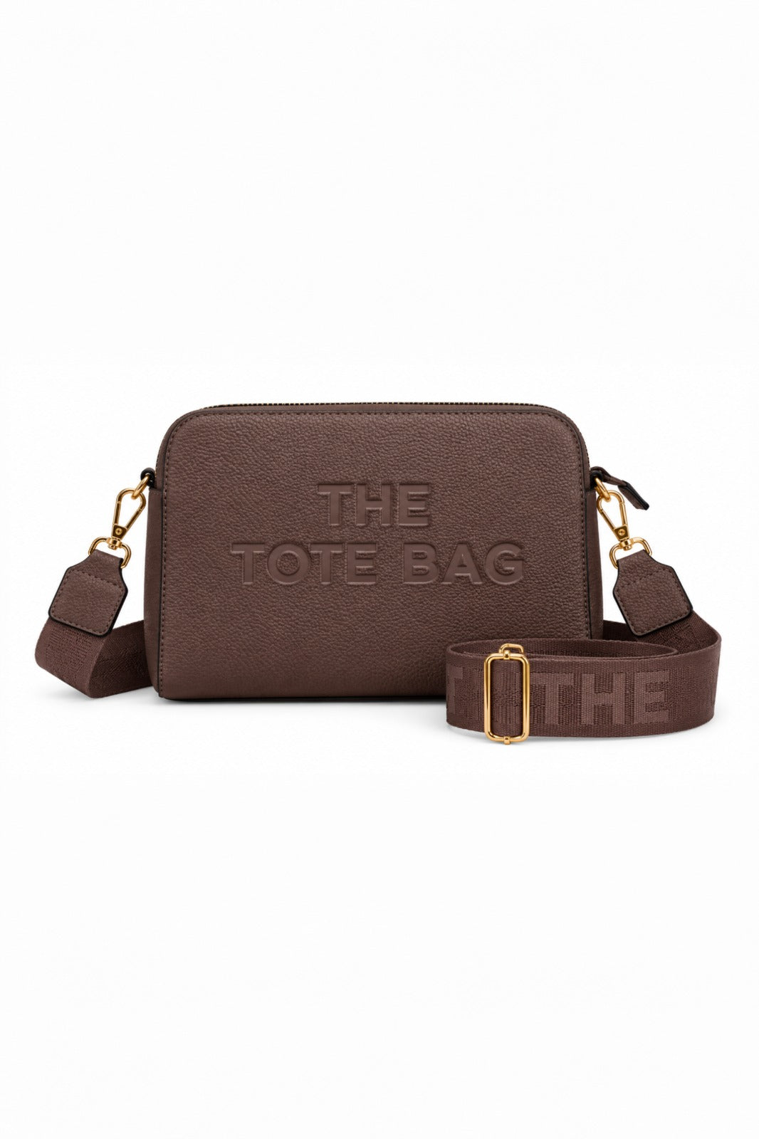 Coffee Brown cross body bag with a rectangular shape, rounded corners, embossed, "THE TOTE BAG" lettering on the front, gold-tone clips and a wide adjustable matching shoulder strap with a gold tone buckle. 