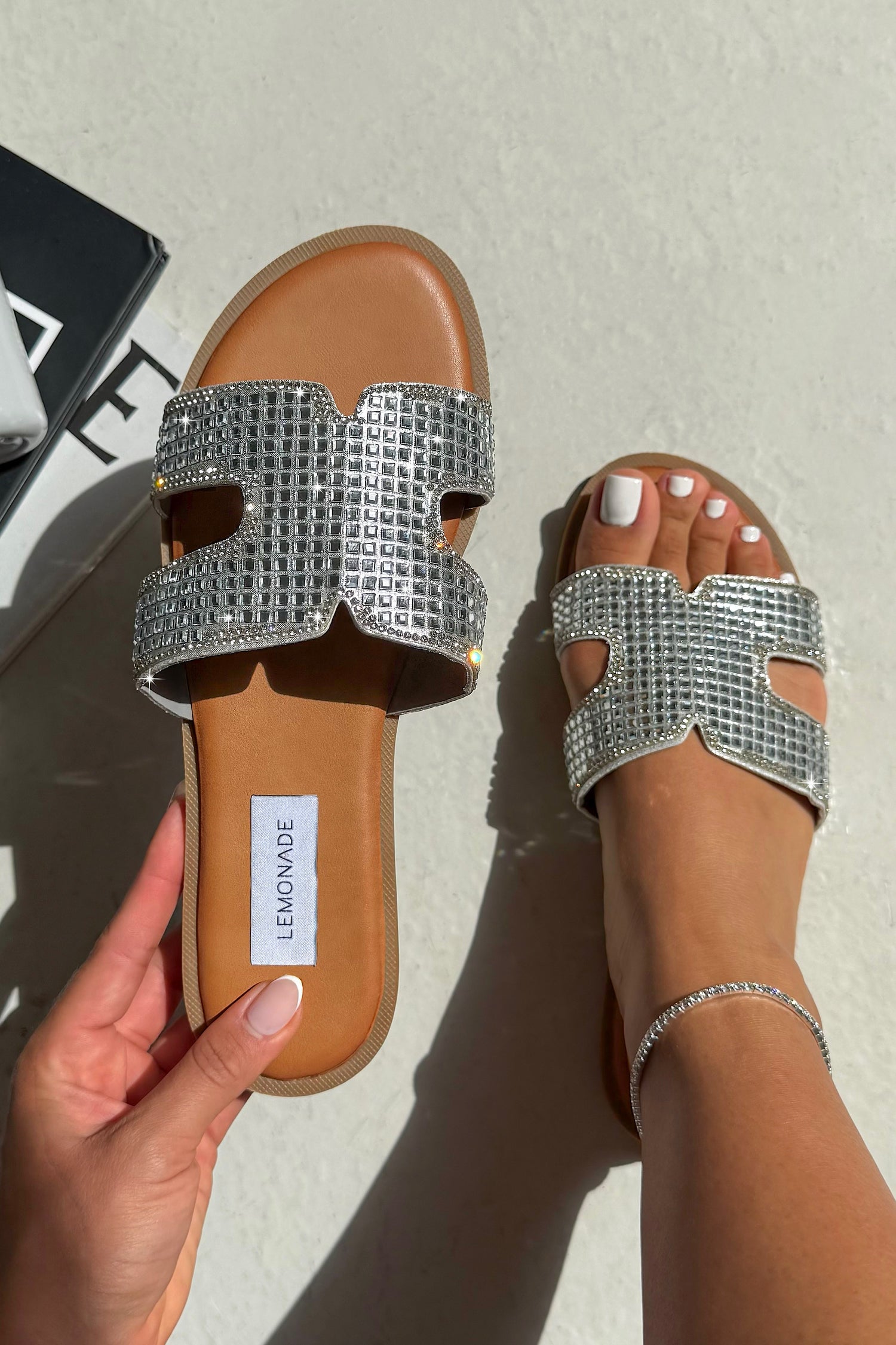 Silver embellished sandals with a visible brand label on a neutral background