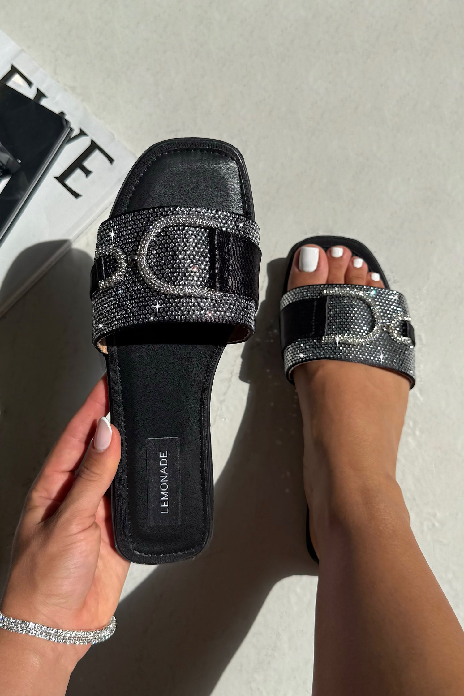 Black sandals with silver embellishments on a light background