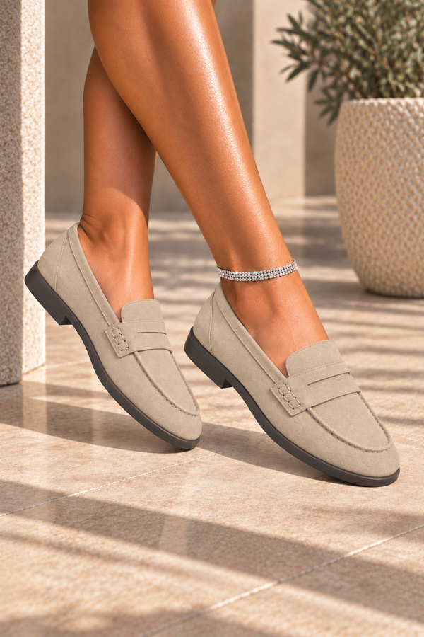 A pair of light taupe suede penny loafers worn on a model&