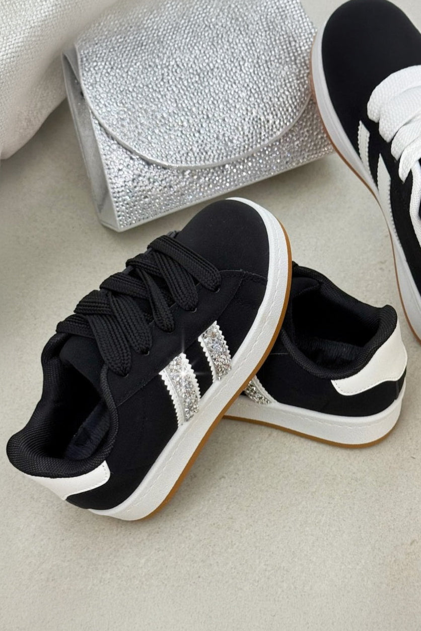 Black and white sneakers with a silver clutch on a light surface