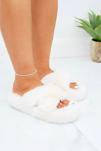 White fluffy slippers worn by a person on a light background
