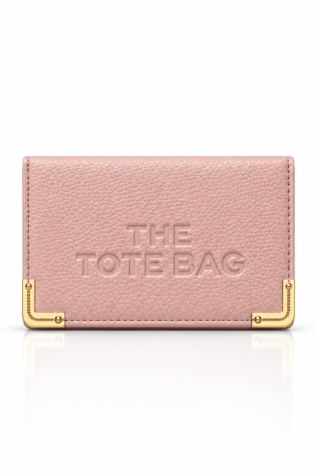 Light pink textured tote bag purse with embossed "THE TOTE BAG" lettering on the front, featuring gold tone metal corner protectors with decorative stud detailing. 