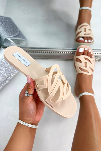 Beige sandals held by a hand with a clear background