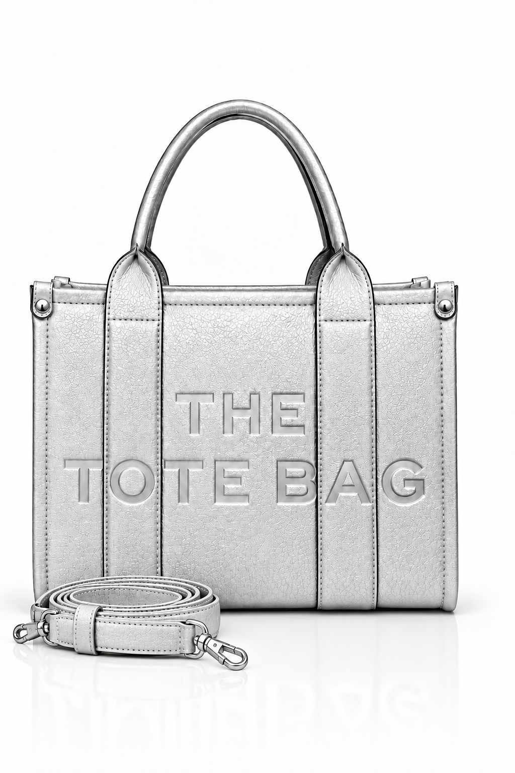 Metallic Silver structured tote bag with two rounded top handles, embossed. "THE TOTE BAG" lettering on the front, vertical stitched panels, contrast edging and silver- tone stud details. With silver-tone strap pictured in front of the bag.