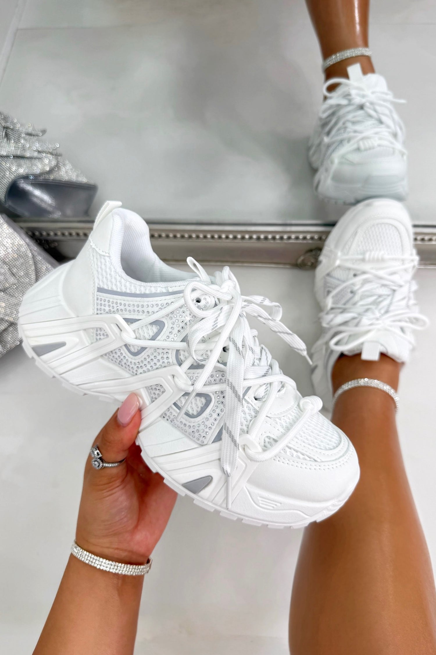 White sneakers being held and worn, with a neutral background
