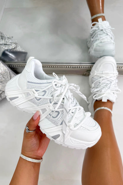 White sneakers being held and worn, with a neutral background