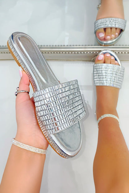 Silver embellished sandals being worn with a white background