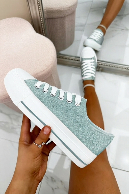 Blue and white sneakers being held with a blurred background