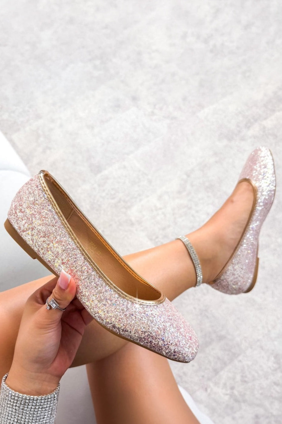 Pink glittery shoes being worn on a textured white background